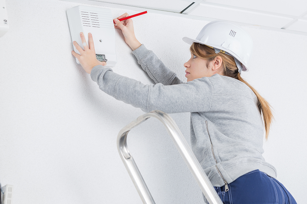 female electrician installing alarm